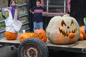 Large and unique carved pumpkins on a trailer with 2 kids watching